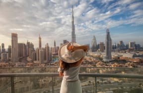 a woman in a hat looking at the dubai skyline