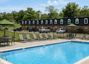 Thumbnail 24 of 24 - A pool surrounded by chairs and umbrellas in front of a brick building.