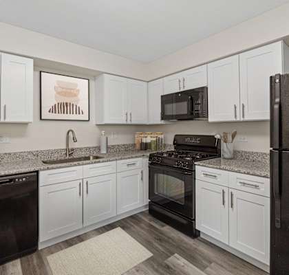 A kitchen with black appliances and white cabinets.