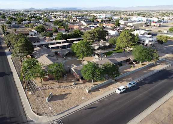 A white car is driving on a road in a residential area.