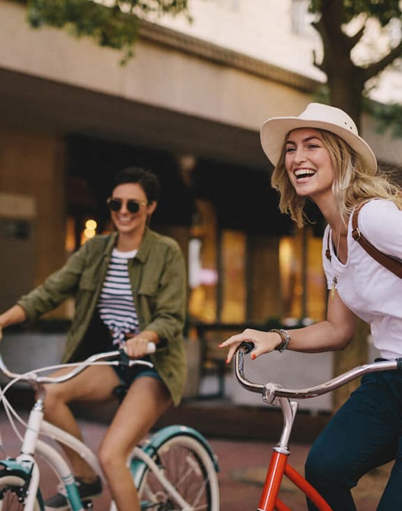 two women riding bikes on a city street