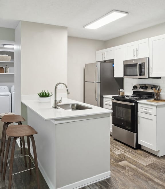 Model Kitchen with White Cabinets and Wood-Style Flooring at Arbor Village Apartments located in Charlotte, NC-SMLAM.