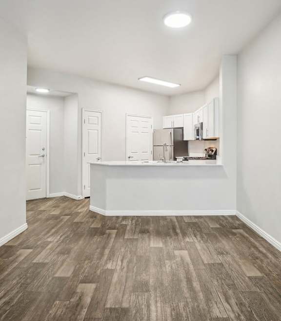 Model Kitchen with Wood-Style Flooring, White Cabinets, and Black Appliances at Altitude on Fifth Apartments located in Salt Lake City, UT.