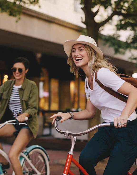 two women riding bikes on a city street