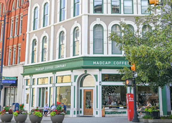 A street view of a Madcap Coffee Company storefront with people sitting outside.