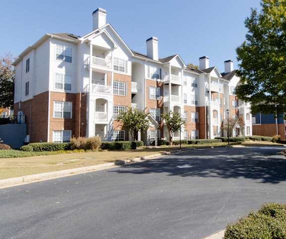 A large apartment complex with a parking lot in front. at The Crest at Sugarloaf, Lawrenceville, GA