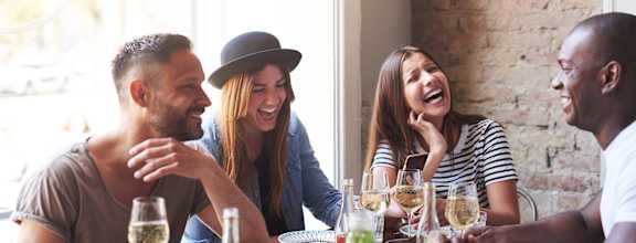 Four people are sitting around a table with food and drinks.