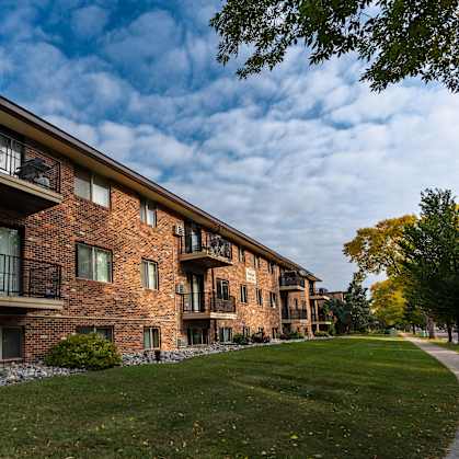 a brick building with three levels and a sidewalk in front. Fargo, ND Emerald Apartments