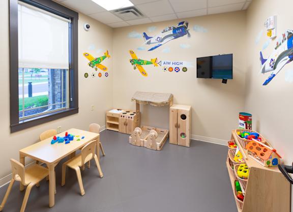 A children's playroom with a wall mural of airplanes and a TV.