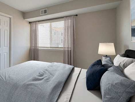 A bedroom with a large bed and a window with curtains.