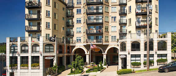 A large, multi-story residential building with balconies and a flag.