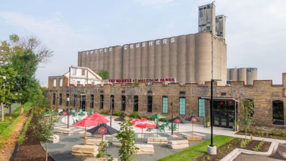 a large brick building with a large number of tables and umbrellas in front of it
