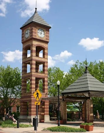 A clock tower stands in front of a gazebo.