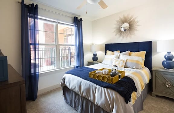 A bedroom with a bed, nightstand, and window with blue curtains.