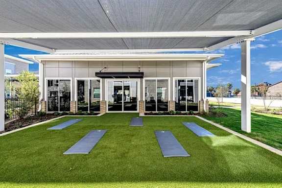 A yoga studio with a white roof and a green lawn in front.
