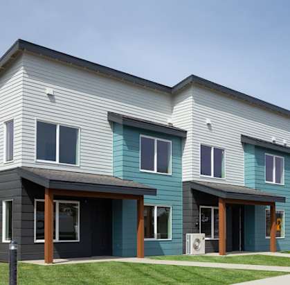 a blue and gray house with a sidewalk and grass