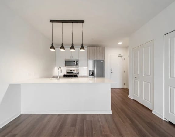 A kitchen with a white counter and wooden floors.
