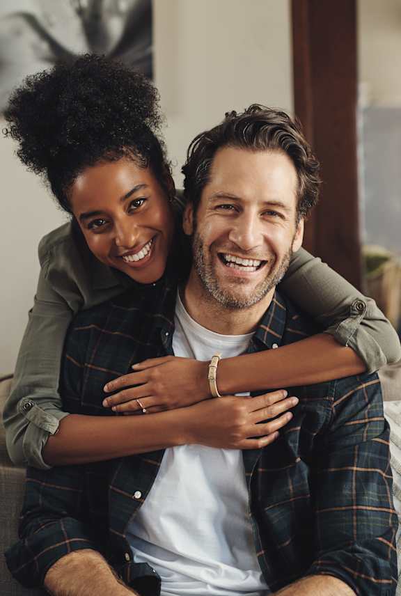A man and woman are sitting on a couch, smiling and embracing each other.