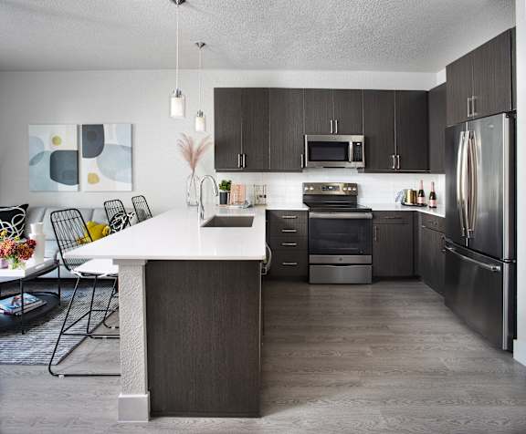 A modern kitchen with dark wood cabinets and stainless steel appliances.