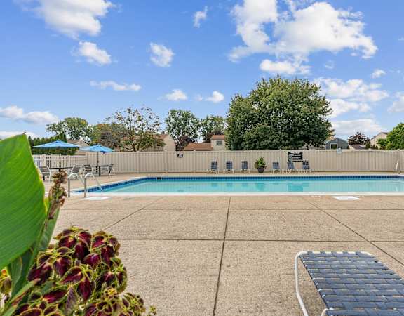 A pool surrounded by a concrete patio and a fence.