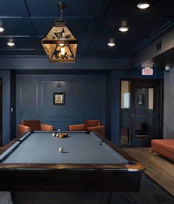 A pool table in a dark room with a chandelier above it at Mercantile on Broadway, Fargo, ND 58102