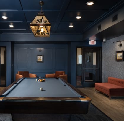 a pool table in a dark room with a chandelier above it