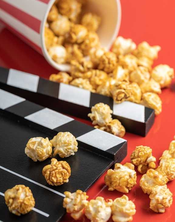 A red and white striped cup is overflowing with popcorn.