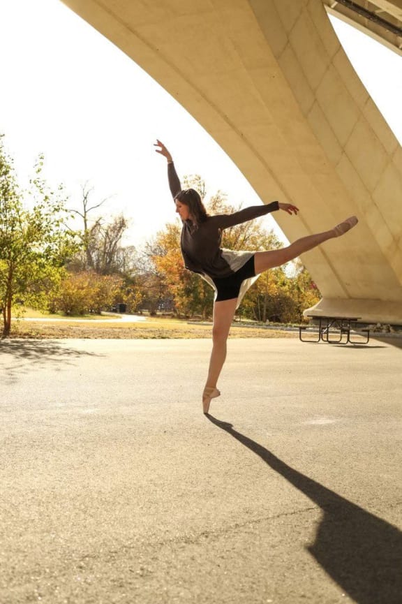 a woman jumping in the air in a parking lot