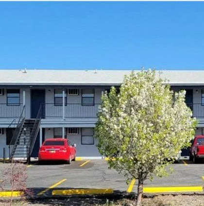 an apartment building with a parking lot and a tree