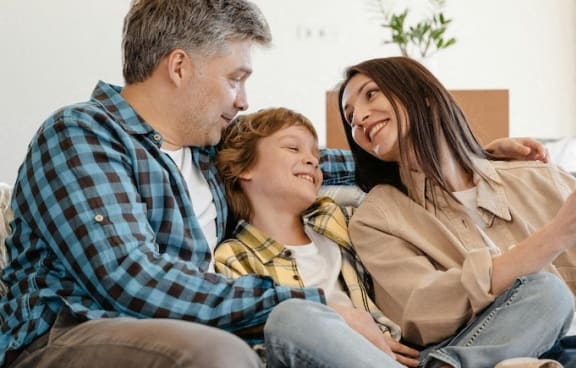a man and woman sitting on a couch with a child