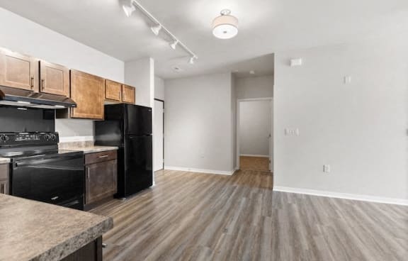 a kitchen and living room with black appliances and wood flooring