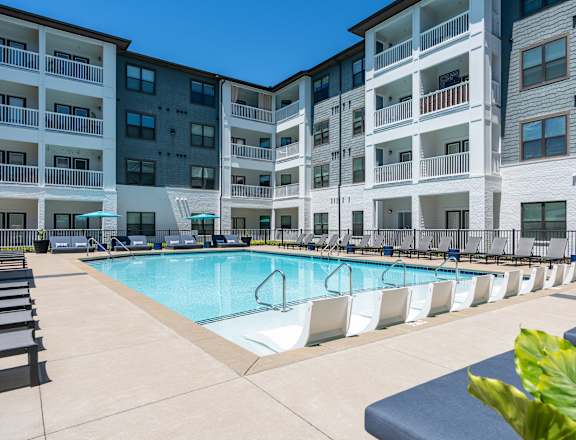 A large swimming pool in front of apartment buildings.
