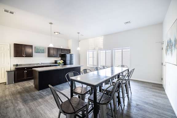 A kitchen with a table and chairs in the foreground and a refrigerator in the background.