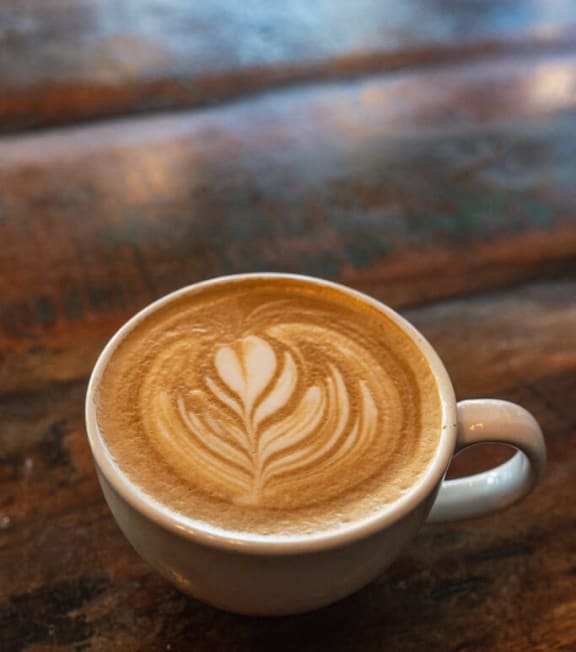 a cup of latte sitting on a wooden table