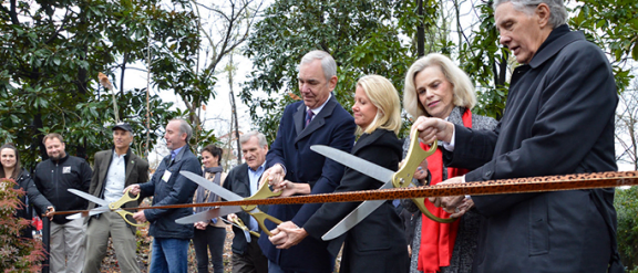 a group of people cutting a ribbon with scissors