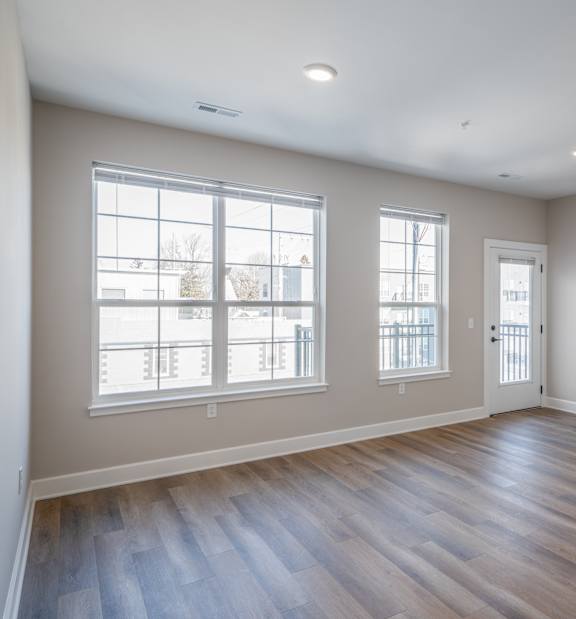 A room with wooden floors and two windows.