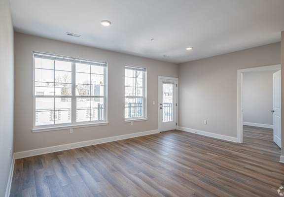 A room with wooden floors and two windows.