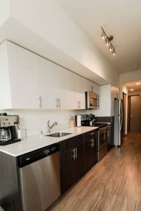 Apartments for Rent Seattle, WA - Apartment Entryway to Kitchen with Stainless Appliances, Modern Cabinetry, and Hardwood Flooring