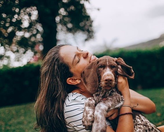 a woman and her dog sitting on the grass