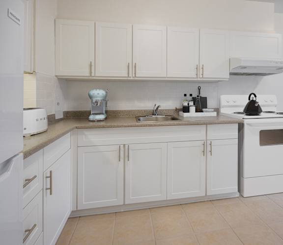 A white kitchen with a sink, stove, and oven.