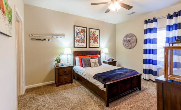 A bedroom with a bed, nightstands, and a ceiling fan.