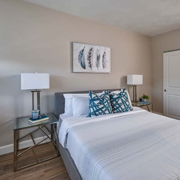 A bedroom with a large bed and a painting on the wall.