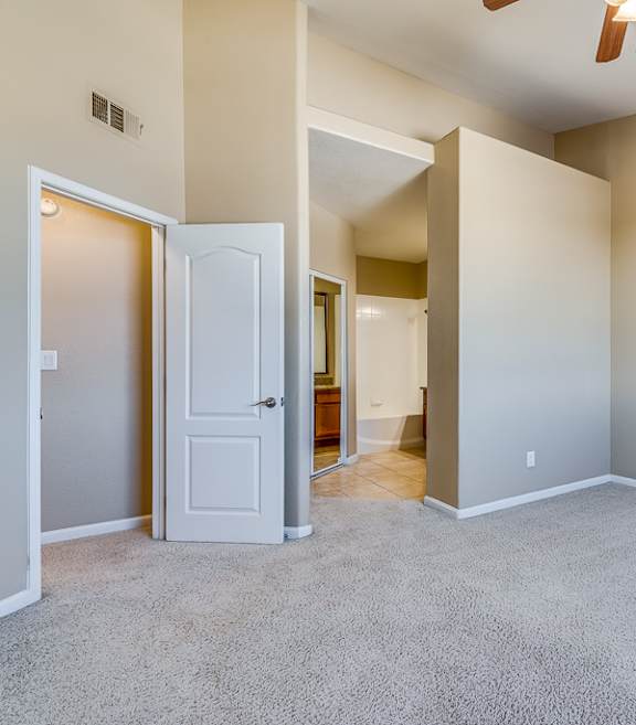 A room with a carpeted floor and a ceiling fan.