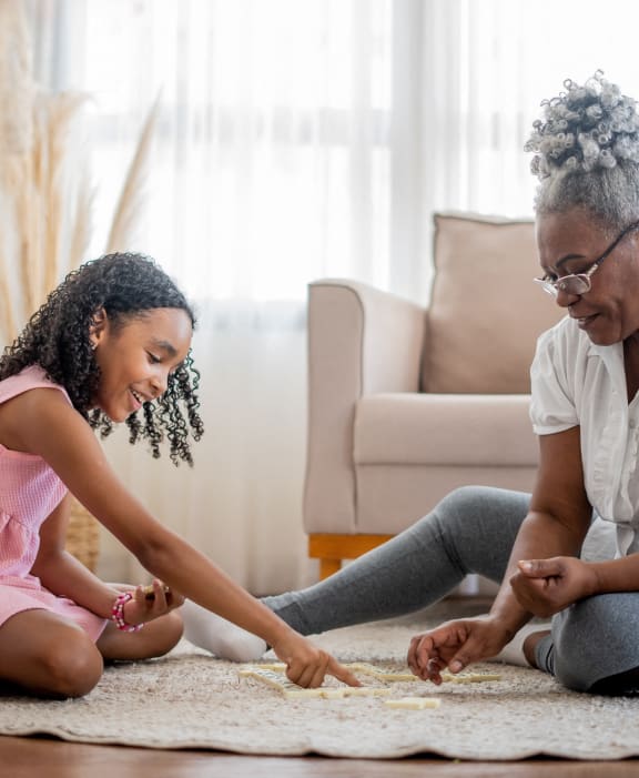 a grandmother sitting on the floor with her granddaughter playing with nail polish