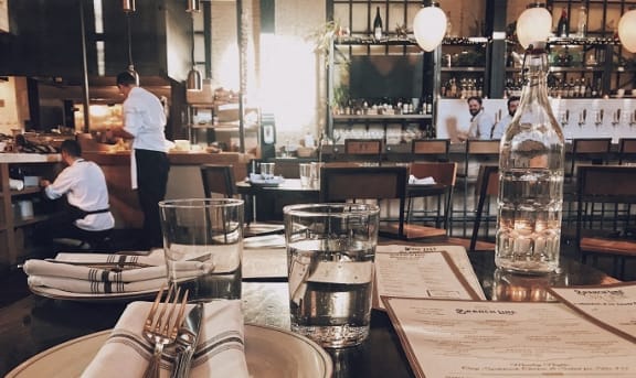 a restaurant table with plates and utensils and a bottle of water