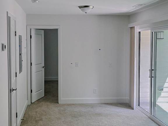 A carpeted hallway with a door on the right.