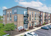 Thumbnail 44 of 59 - A white car is parked in front of a brick apartment building. at Penn Circle, Indiana, 46032