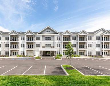 A large white building with a parking lot in front.