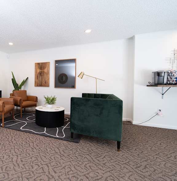 A living room with a brown carpet and a green ottoman.