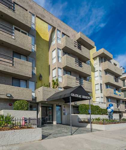 an apartment building with a sidewalk in front of it and a blue sky